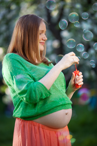 Pregnant woman blowing bubbles outdoor - Foto, afbeelding