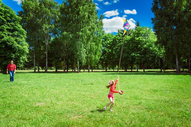 The girl and her father play with a kite. - Фото, зображення
