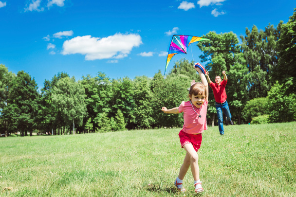 The girl and her father play with a kite. - Фото, изображение
