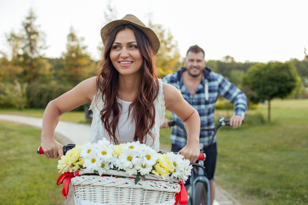 Pretty young girlfriend and boyfriend are driving bicycles - Zdjęcie, obraz