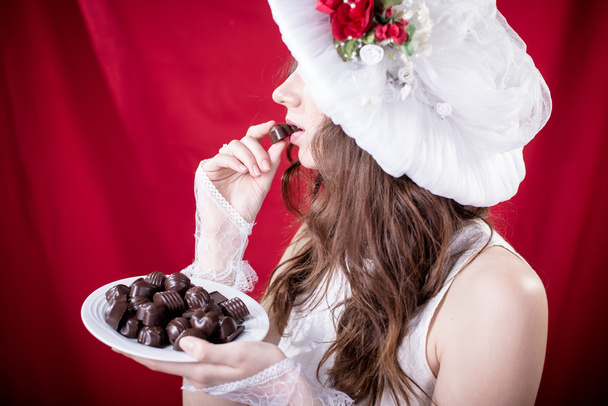 Beautiful young lady in white retro hat eating chocolate - Photo, image