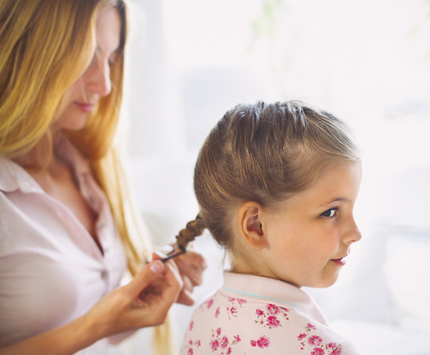 Mother hairdressing her preteen daughter at home - 写真・画像