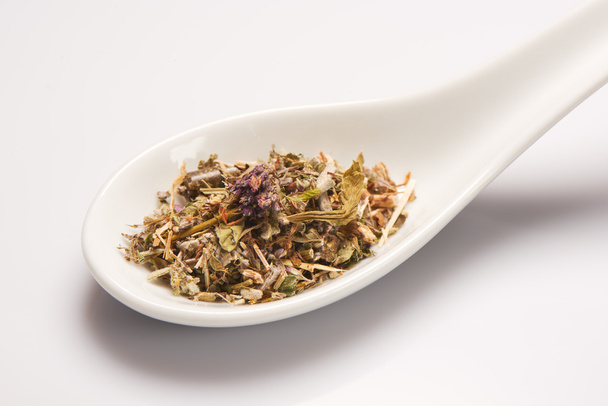 Heap of dry medical herbal tea in white ceramic spoon - Foto, Imagen