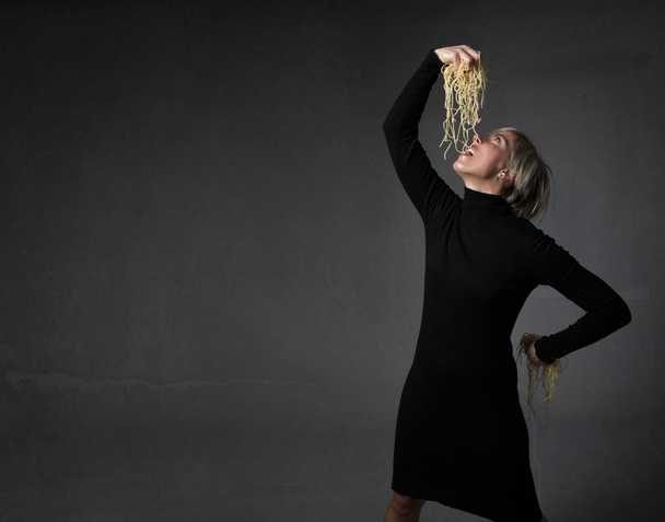 lady eating spaghetti with hands - Фото, изображение