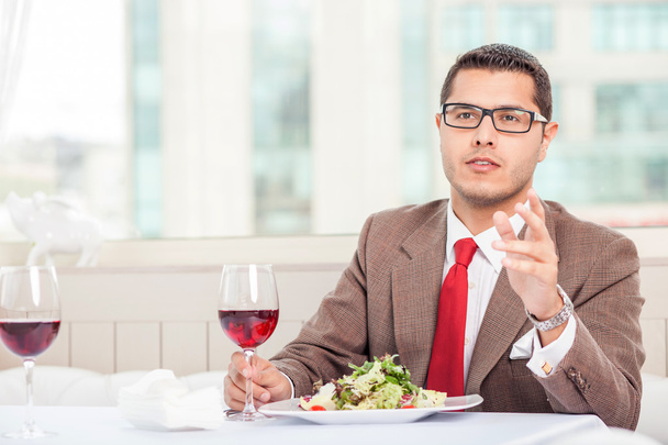 Attractive young man with suit is eating in restaurant - Fotó, kép