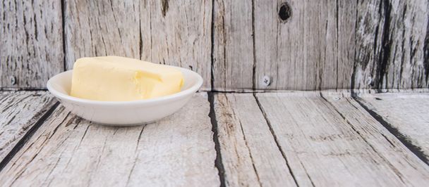 Кусок масла в белой миске на деревенском деревянном фоне
 - Фото, изображение