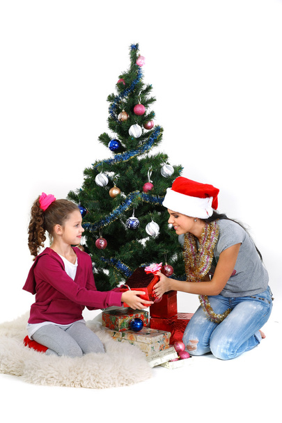 Mother and daughter near a christmas tree with gifts, isolated on a white b - Fotoğraf, Görsel