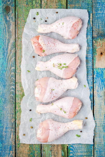 raw organic chicken legs on paper with thym and pepper  - Фото, изображение