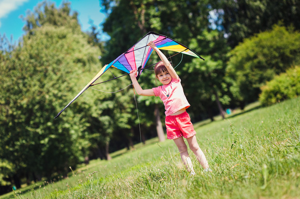 Μικρό κορίτσι Παίξτε με χρωματιστό χαρταετό στο πάρκο.  - Φωτογραφία, εικόνα