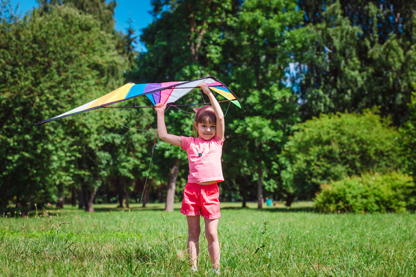 Маленька дівчинка грає з кольоровим змієм у парку
.  - Фото, зображення