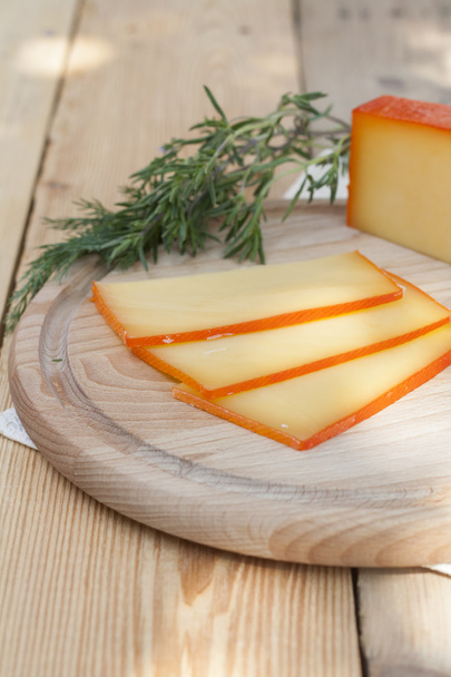 Sliced cheese on wooden board with dill and rosemary, selective focus - Fotoğraf, Görsel