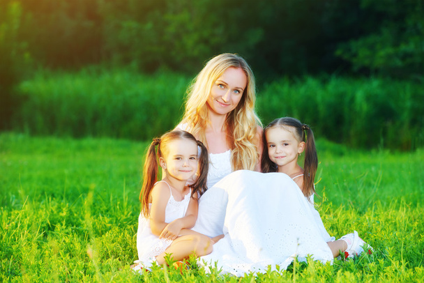 onnellinen perhe äiti ja lapset kaksoset niityllä summe
 - Valokuva, kuva