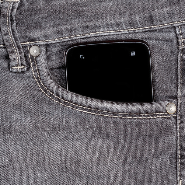 smartphone in the old jeans pocket on wood background - Фото, изображение