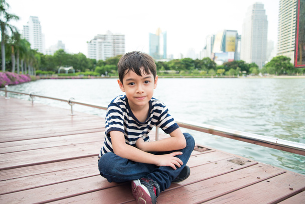 Little boy sitting nearby the lagoon lake in the pard - 写真・画像