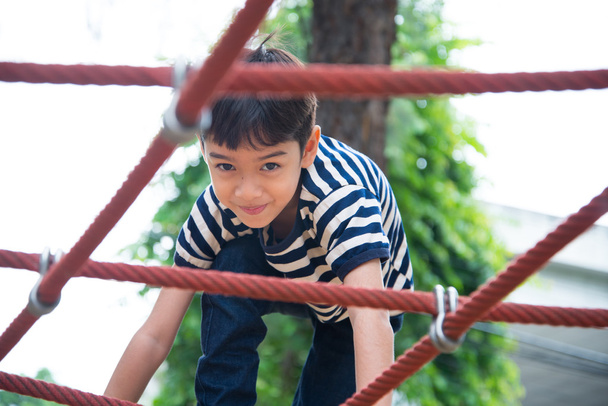 Menino escalando corda no playground
 - Foto, Imagem
