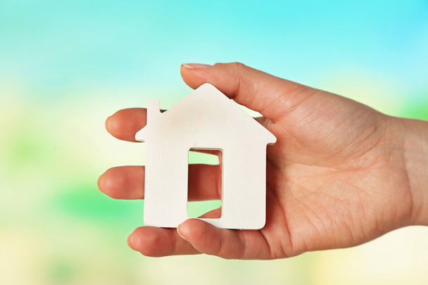 Female hand with model of house on blurred background - Photo, Image