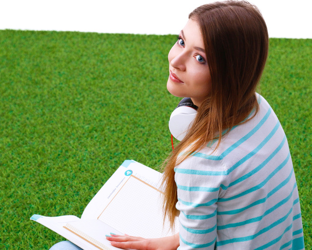 Woman reading book sits on the green grass  - Photo, image