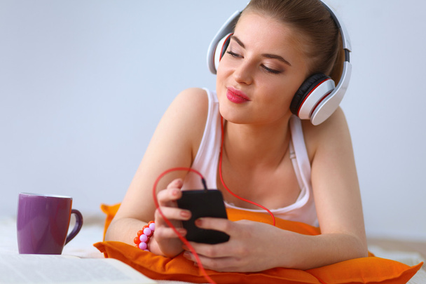 Young woman lying on floor and listen to music - Foto, imagen