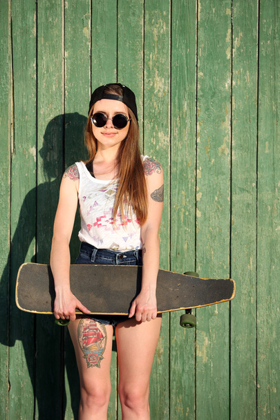 girl with tattooed body, holding skateboard - Photo, Image