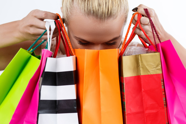 Blond woman inspecting content of colored paper bags with fresh  - 写真・画像