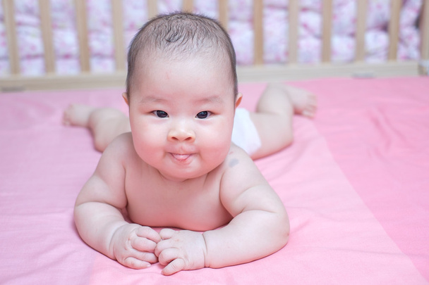 Ázsiai baby girl hazugság rózsaszín ágyon elterült - Fotó, kép