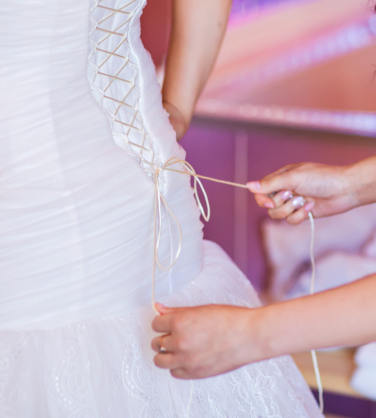 bruidsmeisje is het helpen van de bruid te kleden - Foto, afbeelding