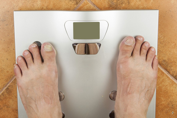 Man looks at a personal scale. Look on her toes, diseased nails. Komcept reducing body weight and dieting. Scale with body fat and muscle. - Foto, Imagem