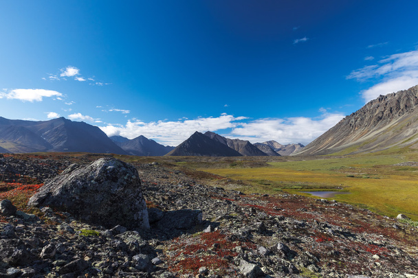 Colorida tundra rocosa frente al valle del río entre la montaña
 - Foto, Imagen