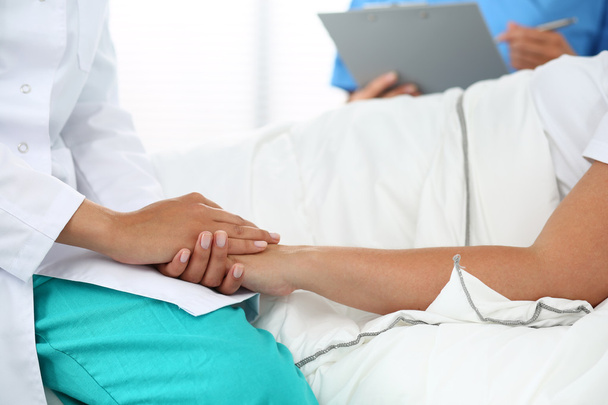 Дружелюбная женщина-врач держит пациента за руку
  - Фото, изображение