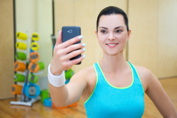 mooie sportieve vrouw maken selfie foto op smartphone in de sportschool - Foto, afbeelding
