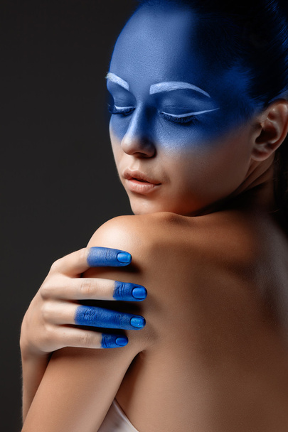 Portrait of a woman who is posing covered with blue paint - Fotó, kép