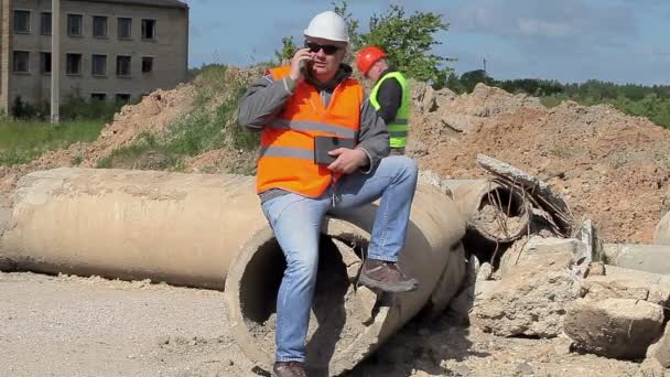 Construction employees with cell phone near building - Felvétel, videó