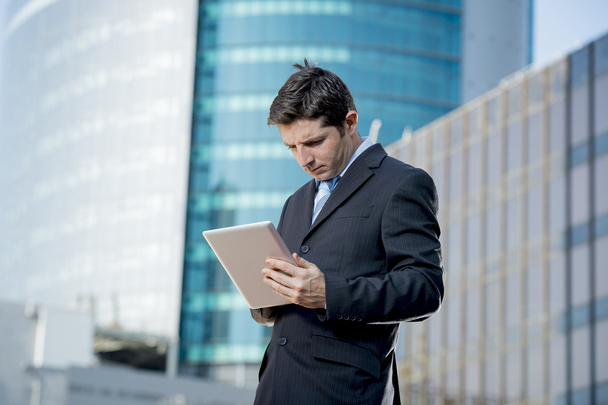 businessman holding digital tablet standing outdoors working business district - Foto, afbeelding