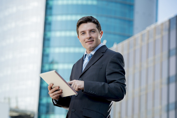 businessman in suit and necktie holding digital tablet standing outdoors working outdoors business district - Foto, afbeelding