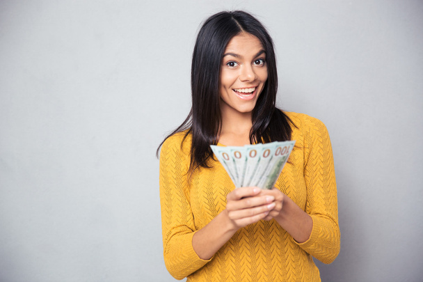 Cheerful woman holding dollar bills - Фото, изображение