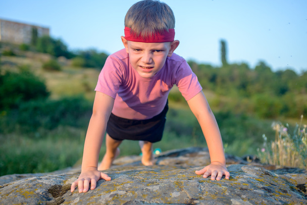 Joven chico haciendo flexiones en una roca
 - Foto, imagen