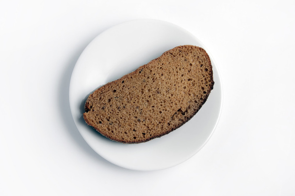 Slice of bread on a white plate on a white background. - Foto, afbeelding