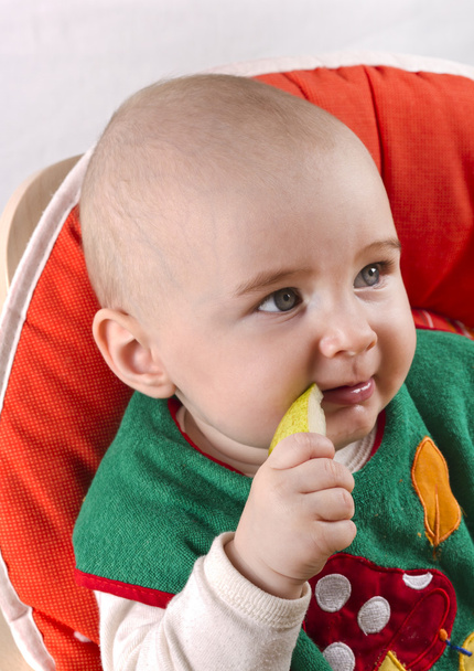Bebé sentado y comiendo una manzana
 - Foto, Imagen