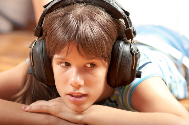 Pretty teenage girl listening to music while lying on the floor - Zdjęcie, obraz