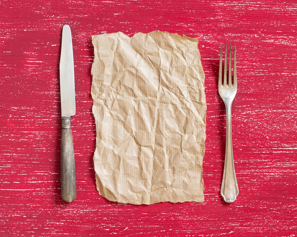 Vintage vork en mes met ambachtelijke papier op rode hout - Foto, afbeelding