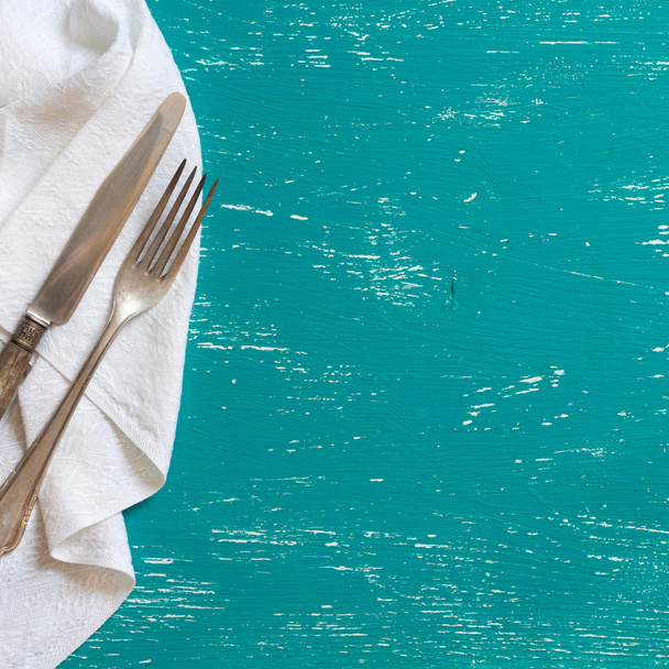 Vintage fork and knife on napkin on turquoise wood - Фото, изображение