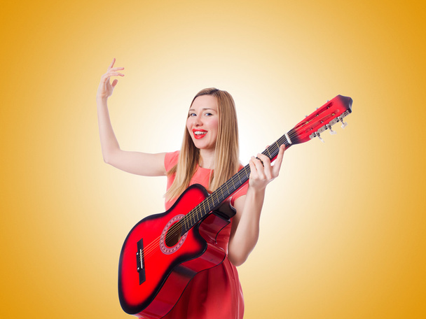 Nainen soittaa kitaraa kaltevuutta vastaan
  - Valokuva, kuva