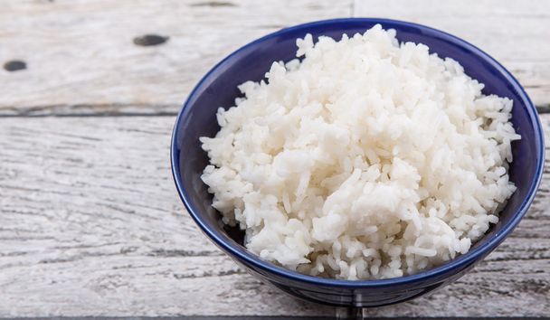 Cooked steamed rice in a blue bowl over wooden background - Photo, Image