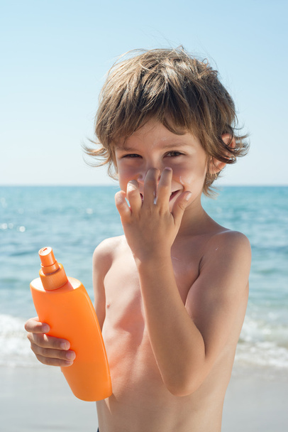 dziecko stosuje krem słońce na jego nos z rąk na plaży - Zdjęcie, obraz