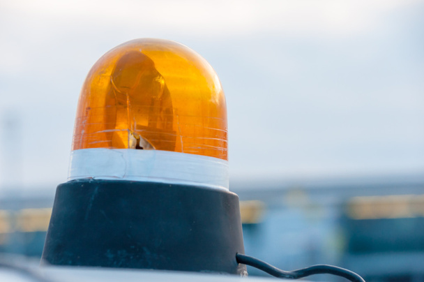Luz intermitente e giratória laranja em cima de um veículo de serviços de apoio
 - Foto, Imagem