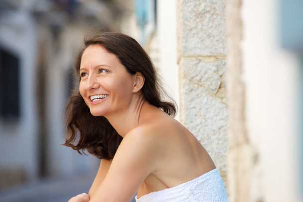 Усміхнена літня жінка сидить надворі
 - Фото, зображення