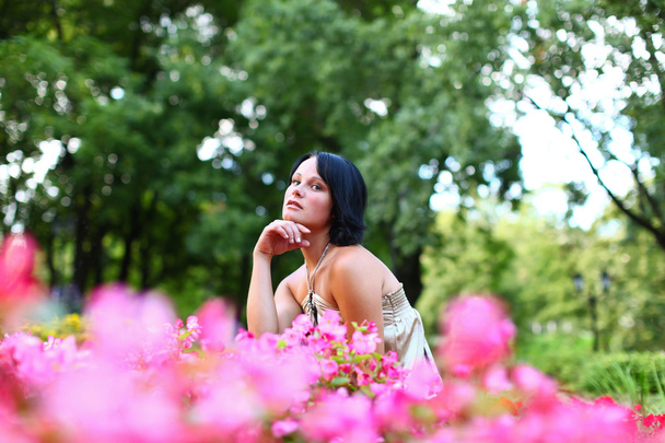 Красива дівчина в парку з рожевими квітами
 - Фото, зображення