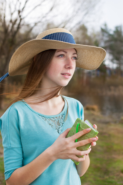 Φακιδωμένος κορίτσι στο καπέλο στέκεται με σημείωση και κοιτώντας μακριά - Φωτογραφία, εικόνα