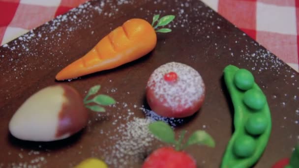 Marzipan fruits are placed on a wooden brown board on a table - Footage, Video