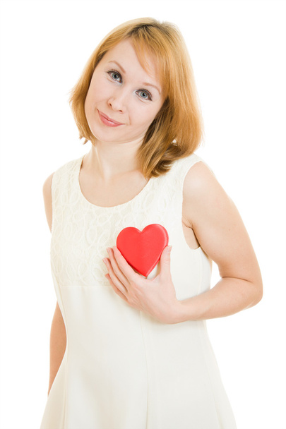The girl pushes the heart to the chest on a white background. - Фото, изображение